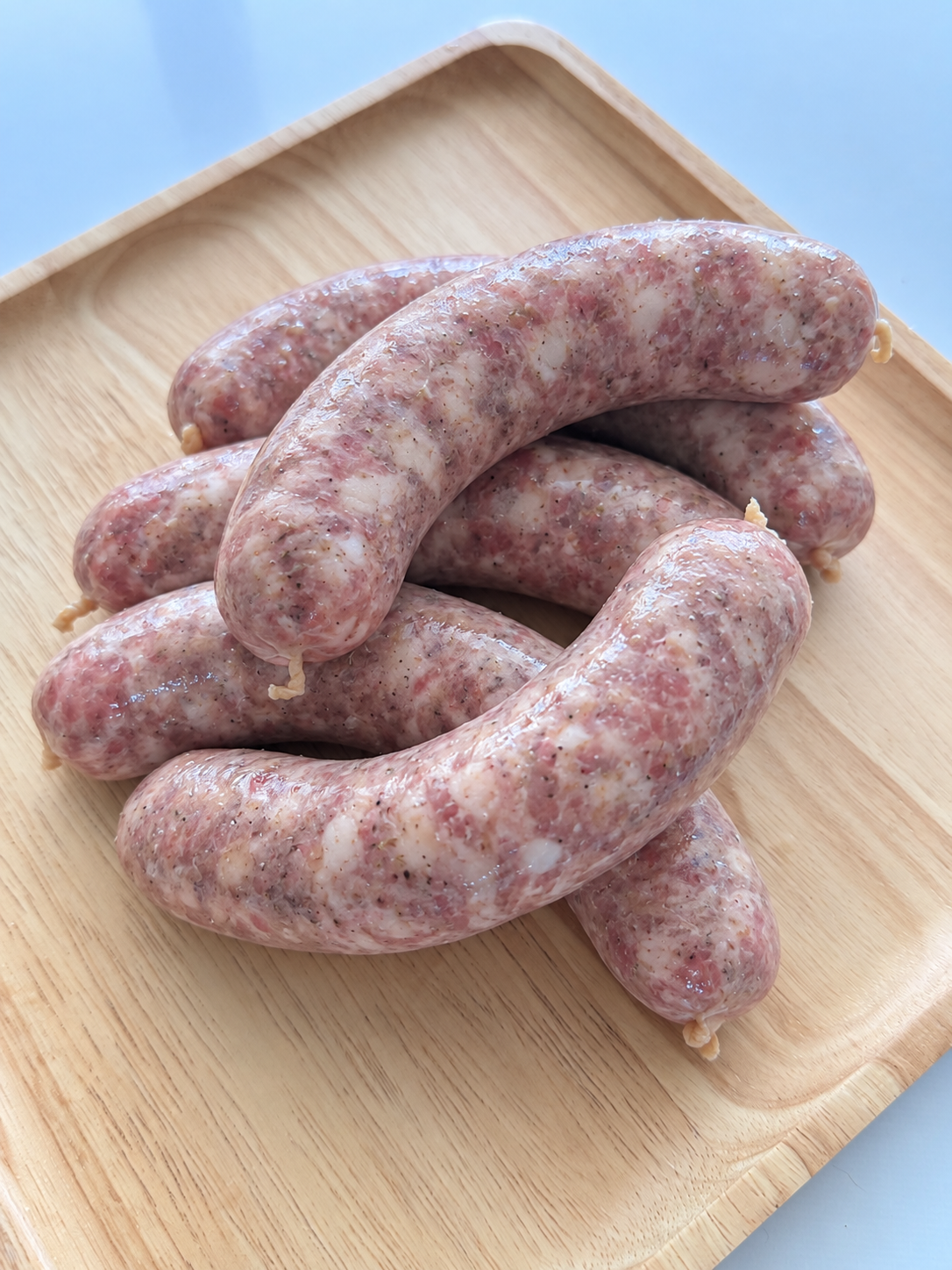 Bauernbratwurst — coarse-ground pork sausages in natural casings on a wooden tray.