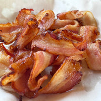 A plate of cooked, crispy honey garlic apple/cherry wood smoked bacon.